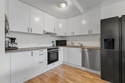 a kitchen with white cabinets and a black refrigerator at Convenient Bergen Stay with Easy Transport Connections in Bergen