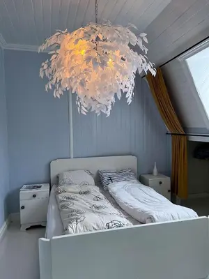 a bedroom with a bed with a chandelier above it at Authentic top floor pearl in the city Center in Ålesund