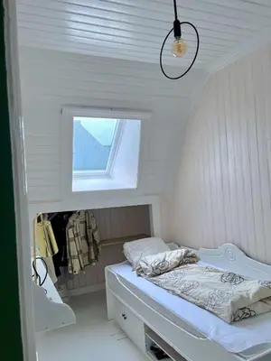 a small white room with a bed and a window at Authentic top floor pearl in the city Center in Ålesund
