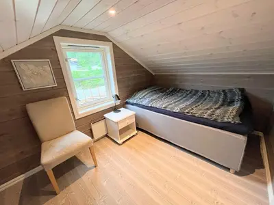 a small bedroom with a bed and a chair at Cozy family cabin with fireplace and near ski trails in Lii
