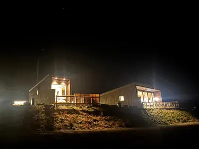 a couple of buildings at night with lights at Unik og moderne microhytte med utsikt mot havet 40 A in Longva