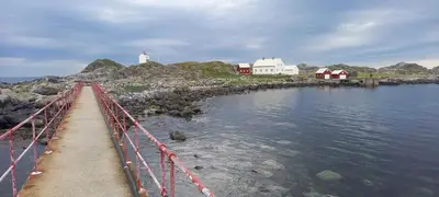 a bridge over a body of water with a lighthouse at Unik og moderne microhytte med utsikt mot havet 40 A in Longva