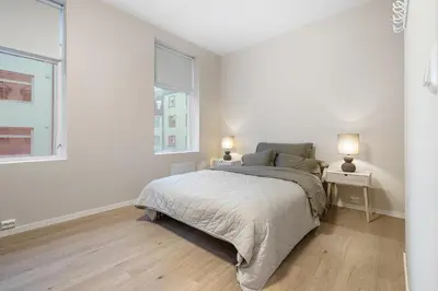 a white bedroom with a bed and two windows at Large apartment, central and quiet in Ålesund in Ålesund