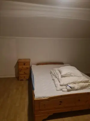 a bedroom with a bed with white sheets and a dresser at Holiday home Hemnskjel in Hitra