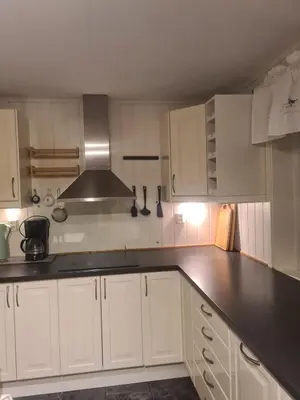 a kitchen with white cabinets and a black counter top at Holiday home Hemnskjel in Hitra