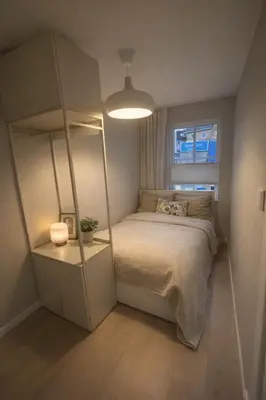 a small bedroom with a bed and a mirror at leilighet in Bergen