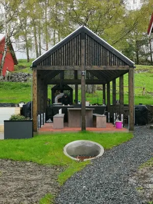 a wooden pavilion with a fire pit in the grass at NerSalberg Farm