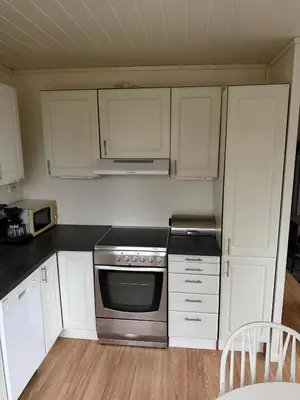 a kitchen with white cabinets and a stainless steel oven at Charming sea view in Bergen