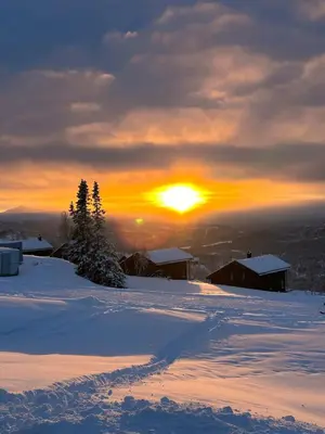 a sunset on a snowy mountain with the sun setting at Modern cabin in Rauland with Panorama view in Torvetjørn
