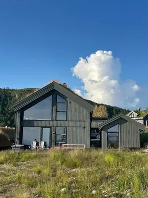 a house with a large glass facade with two chairs at Modern cabin in Rauland with Panorama view in Torvetjørn