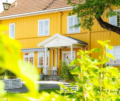 an orange house with a white porch at Granavolden Hotel & Gjæstgiveri in Gran