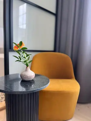 a vase on a table next to a orange chair at Granavolden Hotel & Gjæstgiveri in Gran