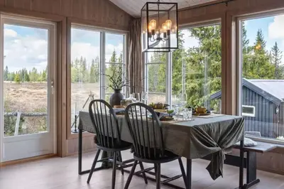 a dining room with a table and chairs and windows at Solglimt, mountain cabin in Golsfjellet with jacuzzi in Gol