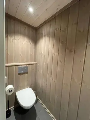 a bathroom with a white toilet and wooden walls at Modern and cozy cabin near ski slopes in Beitostøl