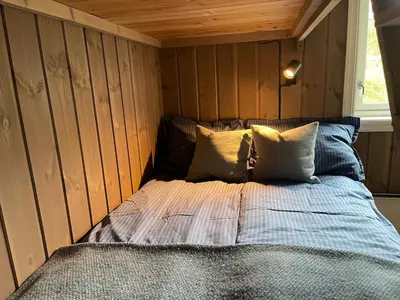 a bed in a room with wood paneled walls at Modern and cozy cabin near ski slopes in Beitostøl