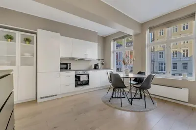 a kitchen with white cabinets and a table and chairs at Bryggen Gateway Homes in Bergen