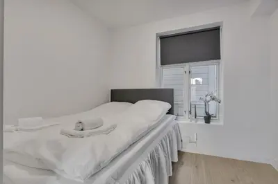 a white bedroom with a large bed with a window at Bryggen Gateway Homes in Bergen