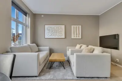 a living room with two white couches and a tv at Bryggen Gateway Homes in Bergen
