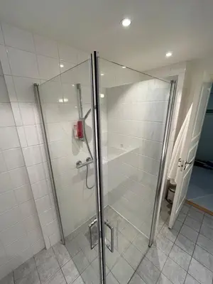 a shower with a glass door in a bathroom at Nice and central apartment in Sandviken with sea view in Bergen