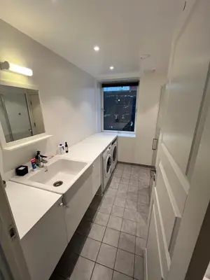 a white kitchen with a sink and a washing machine at Nice and central apartment in Sandviken with sea view in Bergen