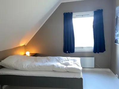a bedroom with a bed with blue curtains and a window at 5 Bedroom House at Hakallestranda in Sandvik
