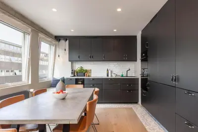 a kitchen with black cabinets and a wooden table at Nice apartment with three bedrooms in the middle of Bergen! in Bergen