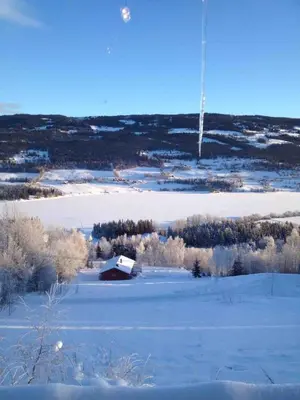 a snow covered field with a barn in the distance at Lite hus i Vestre Slidre in Slidre