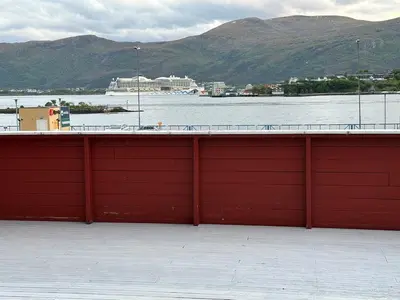 a red wall on a building next to a body of water at Apartment centrally with garage and terrace in Ålesund
