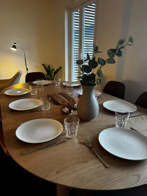 a wooden table with white plates and a vase on it at Big apartment - Prime Location - Middle of Voss in Vossevangen