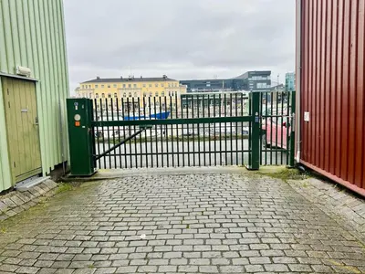 a black metal gate with a brick walkway next to a building at Riverside studioapartment 100m from trainstation! in Trondheim