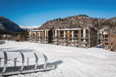 a ski lodge in the snow in front of a building at Modern ski-in-ski-out apartment in Hemsedal in Hemsedal