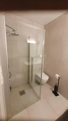 a bathroom with a glass shower with a toilet at Flott leilighet med nydelig utsikt i et stille og rolig boligområde in Bergen