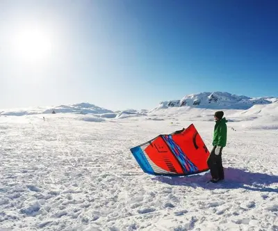 a man standing in the snow holding a kite at Great mountain cabin with 12 beds in Vågsli