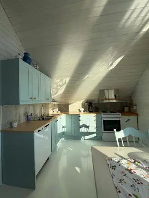 a kitchen with white cabinets and a table and chairs at Cabin by the lake in Sveio