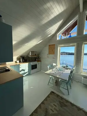 a kitchen with a table and chairs in a room at Cabin by the lake in Sveio
