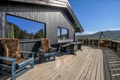 a deck with two chairs and a table on a house at Cabin in Hovden with Beautiful views in Bykle