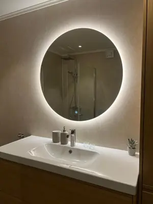a bathroom with a sink with a round mirror at Nyoppusset leilighet i sentrum in Verdal