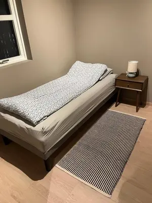 a bed in a room with a nightstand and a bed sidx sidx at Nyoppusset leilighet i sentrum in Verdal