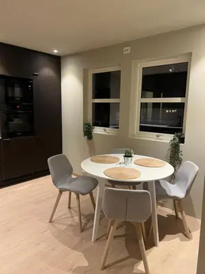 a dining room with two tables and chairs and two windows at Nyoppusset leilighet i sentrum in Verdal