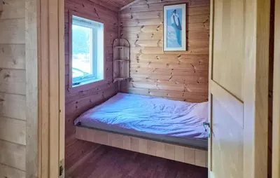 a bed in a wooden cabin with a window at 3 Bedroom Stunning Home In Tansøy in Tansøy