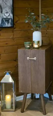a wooden side table with a candle and a vase at Well-Equipped Cabin Near Rauland Alpine Centre in Rauland