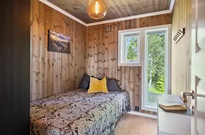 a bedroom with wooden walls and a bed with yellow pillows at Family Cabin BUDOR - 60 MIN FROM OSL - Alpine Cross Country Skiing in Løten
