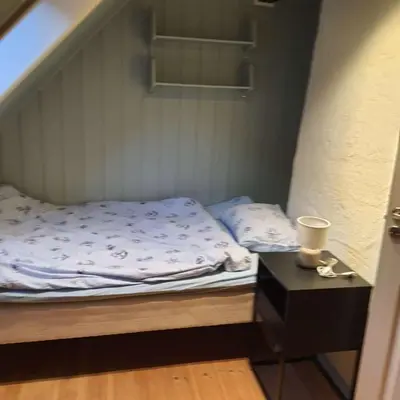 a small bed in a small room with a night stand at Great apartment overlooking Bergen in Bergen