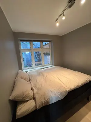 a bed in a bedroom with a window at Stylish 2BR with Patio and Smart TV - 10 min to Bryggen in Bergen