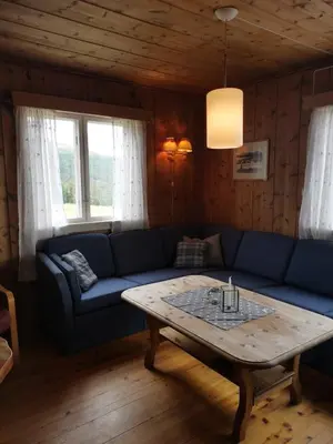 a living room with a blue couch and a coffee table at Åsrud seter i Jotunheimen in Vaga