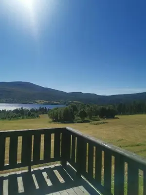 a deck with a view of a field and a lake at Åsrud seter i Jotunheimen in Vaga