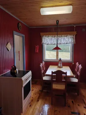 a dining room with a table and a kitchen at Åsrud seter i Jotunheimen in Vaga