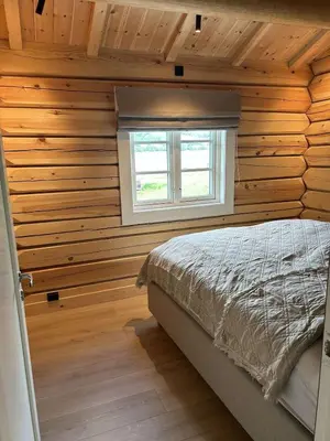 a bedroom with wooden walls and a bed with a window at Gunhild-stugu i Jotunheimen