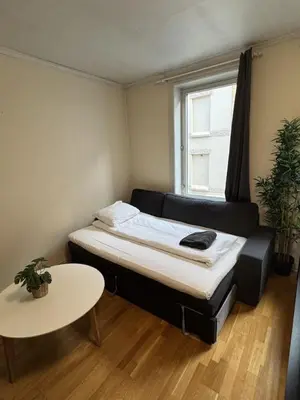 a small bedroom with a bed and a table at Cozy Studio in Lademoen, Trondheim in Trondheim