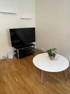 a living room with a white table and a tv at Cozy Studio in Lademoen, Trondheim in Trondheim